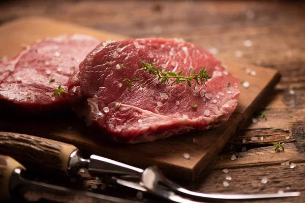 Bife cru e especiarias em tábua de corte de madeira — Fotografia de Stock