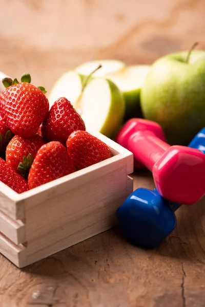 Apple, strawberry, dumbbells, on wooden table