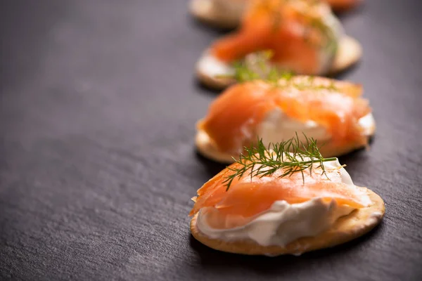 stock image Canapes with salmon isolated on black background