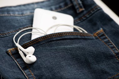 Mavi kot pantolon ve beyaz kulaklık ön cebinde Smartphone