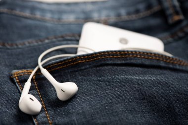 Mavi kot pantolon ve beyaz kulaklık ön cebinde Smartphone