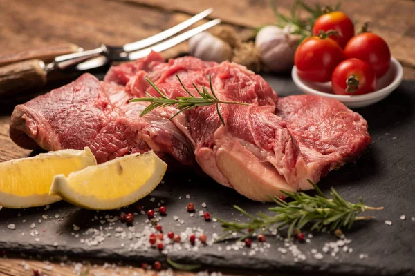Carne fresca cruda en una tabla de cortar negra — Foto de Stock
