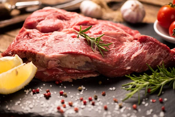 Carne fresca cruda en una tabla de cortar negra — Foto de Stock