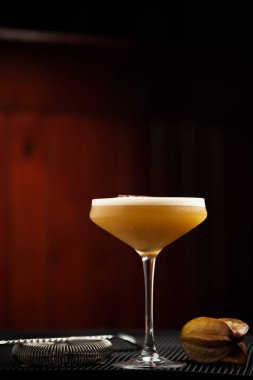 Kahverengi arka planda uzun bardakta çarkıfelek meyveli kokteyl.