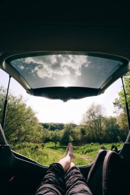 Adam arabanın bagajında oturmuş ormana bakıyor. Güzel manzara manzarası. Yolculuk konsepti