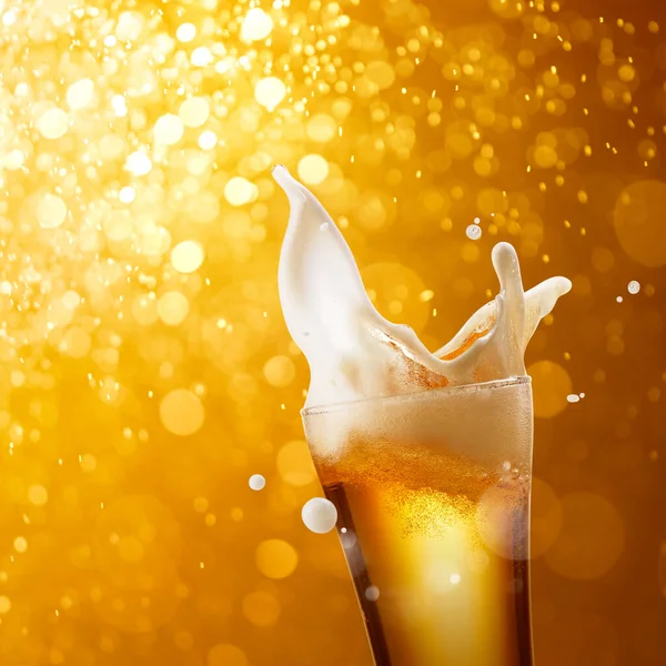 Altın Bokeh Arka Planında Bir Bardak Sıçratan Bira — Stok fotoğraf