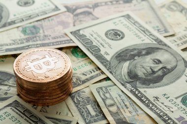 Dolar banknotları üzerine yığılmış Bitcoin paraları.