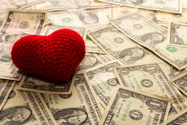 Red heart woven on dollar currency bills, love of money.