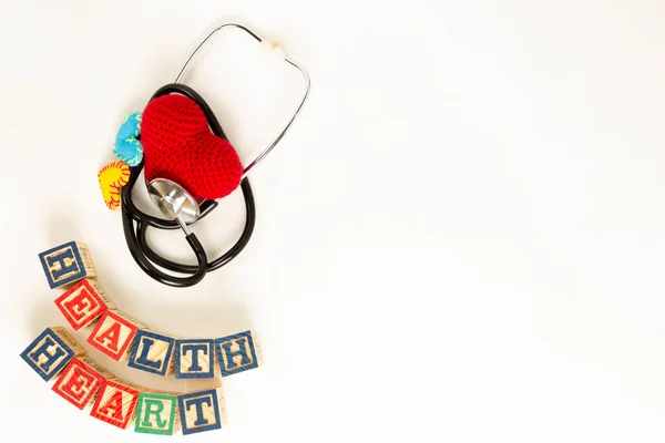 Heart health and prevention concept. Stethoscope and red heart of crochet on white isolated background with space for text.