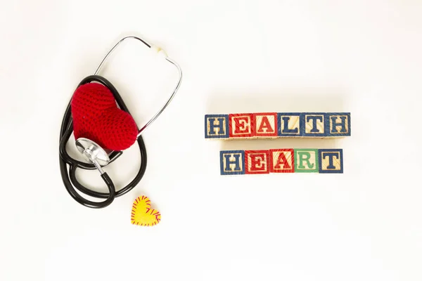 Heart health and prevention concept. Stethoscope and red heart of crochet on white isolated background with space for text.