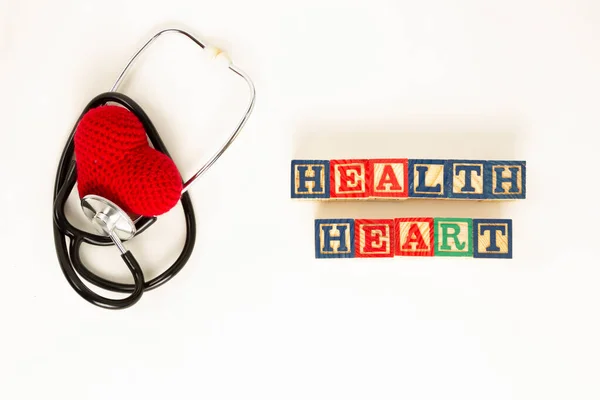 Heart health and prevention concept. Stethoscope and red heart of crochet on white isolated background with space for text.