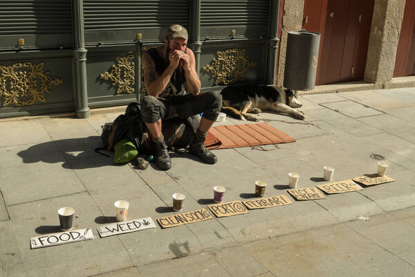 Porto, Portugal - April 22, 2018: Young tramp asking for money in streets of Porto, Portugal during spring 2018. He is very original