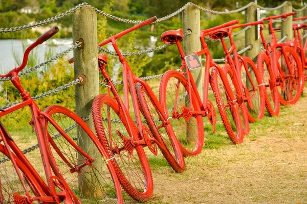 Red painted bicycles propped against the fence near Taupo lake — Stock Photo, Image