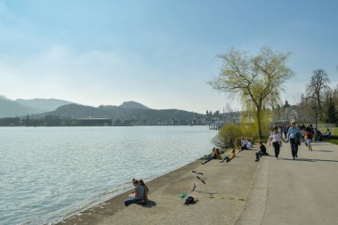 Luzern, Swit'teki Lucerne Gölü'nün yanındaki gezinti yolunda yürüyen insanlar