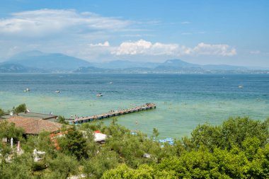 Sirmione, İtalya - 19 Temmuz 2019: İnsanlar Temmuz 2019 'da İtalya' nın Sirmione kentindeki küçük plajda Garda Gölü 'nde yaz günlerinin tadını çıkarıyorlar.