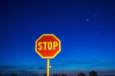 Gece şehir içinde dur işareti. Trafik yönetmeliği. Mavi gökyüzü.