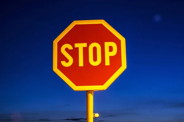 Stop sign in the night city. Traffic regulation. Blue sky.