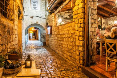 Trogir, Hırvatistan - 26 Temmuz 2017: Stone street Trogir, Hırvatistan'ın eski şehir. Geleneksel restoran ile gece sahne. Seyahat hedef.