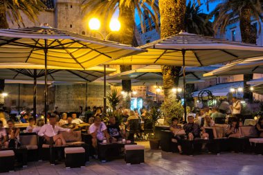 Trogir, Hırvatistan - 25 Temmuz 2017: Çok sayıda turistin gece, Trogir, Unesco, Hırvatistan bir açık hava barda rahatlatıcı vardır. Seyahat hedef. Yaz tatili. Açıklayıcı yazı işleri.