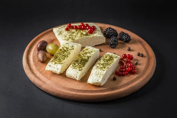 Käse auf Holzbrett mit Beeren, Oliven und Pfeffer — Stockfoto