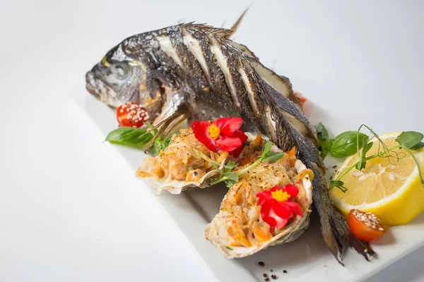 Dorada soutenue avec salsa en coquille, vert, tomates, fleurs rouges et citron — Photo gratuite