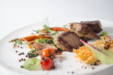 Peynir, havuç, soğan, yeşil ve beyaz tabakta domates ile pişmiş et.