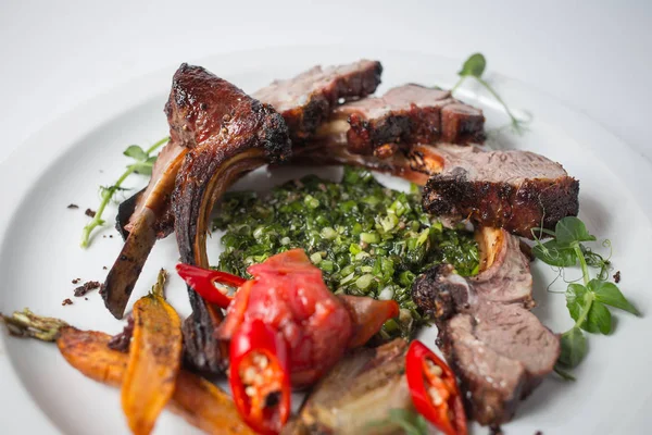 Baked lamb with carrot, onion, chili, green, carrot, green and tomatoes on white plate