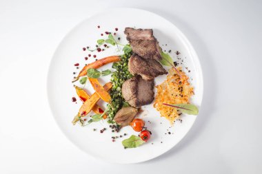 Peynir, havuç, soğan, yeşil ve beyaz tabakta domates ile pişmiş et.