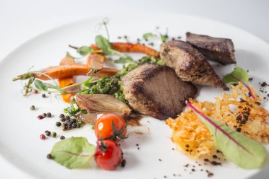 Peynir, havuç, soğan, yeşil ve beyaz tabakta domates ile pişmiş et.