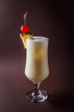 Pina colada berry ve zarif koyu kahverengi zemin üzerinde ananas ile bardak.
