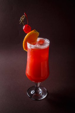 Kırmızı alkol kiraz ve zarif koyu kahverengi zemin üzerine portakal dilim ile kokteyl bardak.