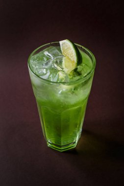 Bardak mojito buz ve zarif koyu kahverengi zemin üzerine kireç dilim.