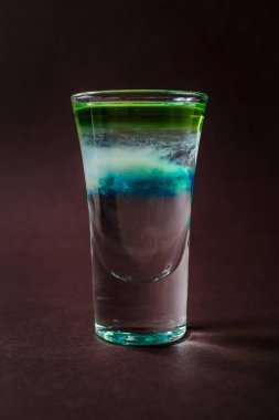 Bulutlar alkolik ile cam yok, sambuca, tekila, blue curacao zarif koyu kahverengi zemin üzerinde vurdu..