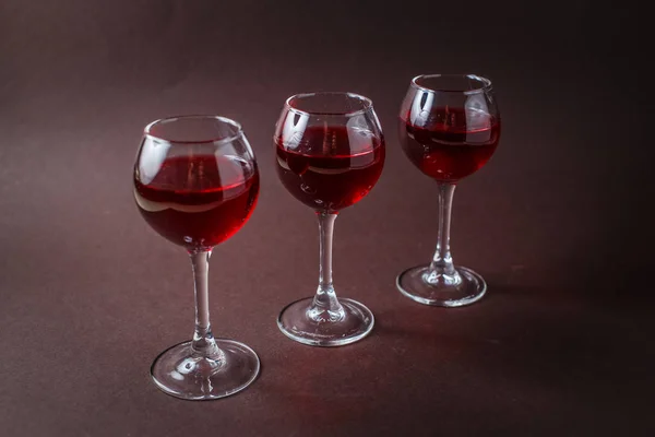 3 küçük zarif koyu kahverengi zemin üzerine kırmızı likör bardak.