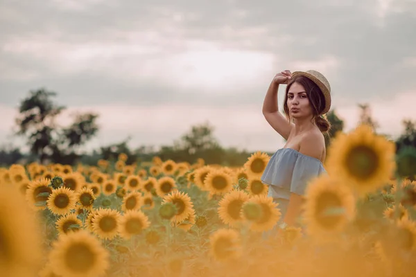 梦到穿着蓝色衣服的年轻女子 夏天在向日葵的田野里拿着帽子 前面的风景 向一边看去 黄色耀斑 复制空间 — 图库照片
