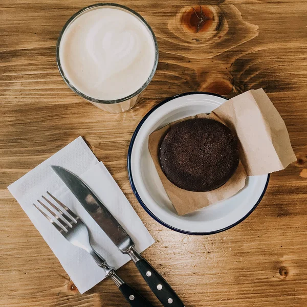 木製のテーブルの上にコーヒーとチョコレートケーキのカップ。ヴィンテージフォークとナイフスクレッド写真。ヴィンテージ料理  — 無料ストックフォト