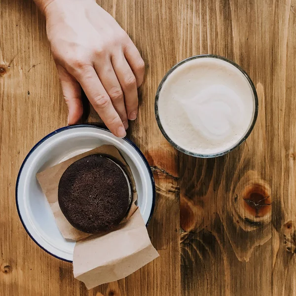 Ceașcă de cafea și tort de ciocolată pe masă de lemn. Mâna atinge un tort. Fotografie Squred. Vintage antena — Fotografie, imagine de stoc