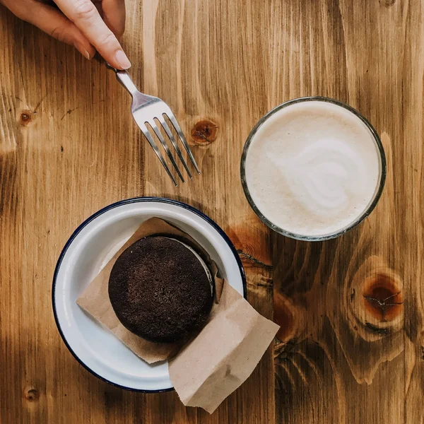 Ceașcă de cafea și tort de ciocolată pe masă de lemn. Mâna cu o furculiță atingând un tort. Fotografie Squred. Vintage antena — Fotografie, imagine de stoc