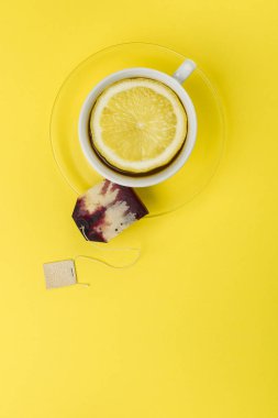 çay limon dilimi ve sarı masa örtüsü üzerinde çay poşeti