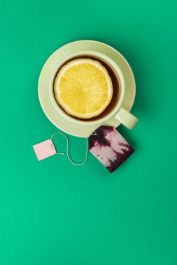 çay limon dilimi ve yeşil masa örtüsü üzerinde çay poşeti