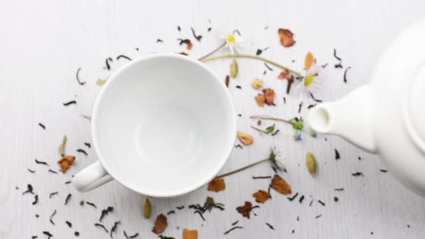 konvice čaj nalil do poháru na bílém stole