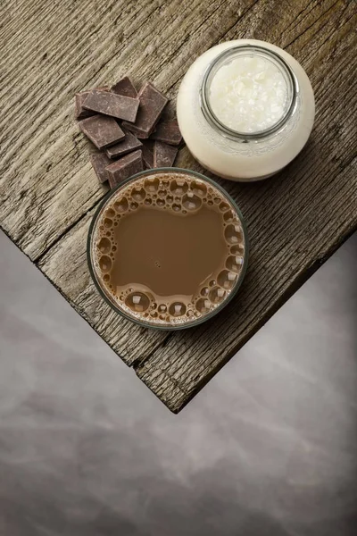 Çikolata çikolata bloklar ahşap masa üzerinde cam ve süt şişesiyle.