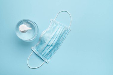 Mavi arka planda antibakteriyel jeli olan cerrahi koruyucu yüz maskesi.