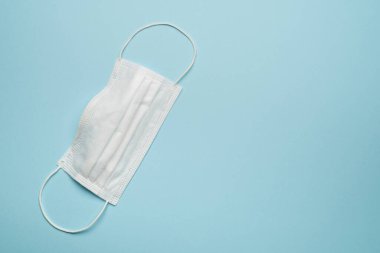 Mavi arka planda cerrahi koruyucu yüz maskesi.