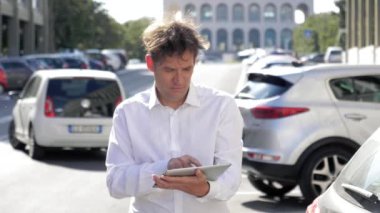 Adam sokakta şehrin trafik yavaş hareket ile tablet e-posta kontrol