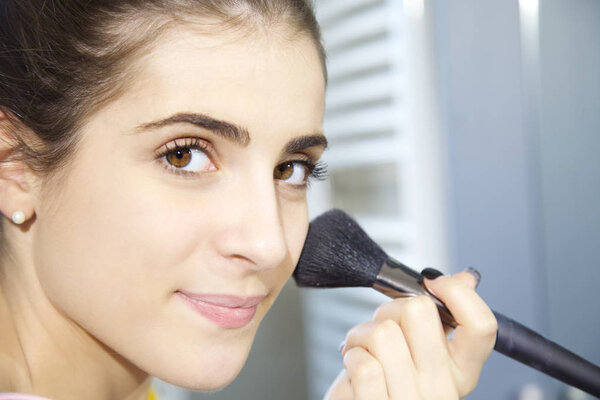 Happy woman putting makeup