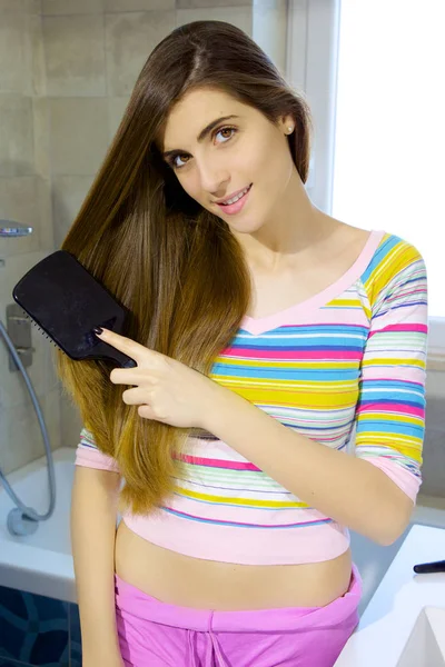 Bonito jovem mulher escovação longo cabelo sorrindo — Fotografia de Stock