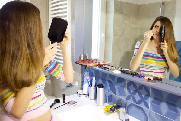 Mujer desesperada por la pérdida de cabello frente al espejo en el baño — Foto de Stock