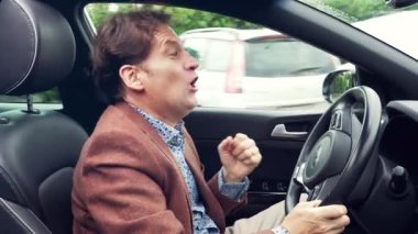 Mutlu genç iş adamı araba sürerken şarkı söylüyor.