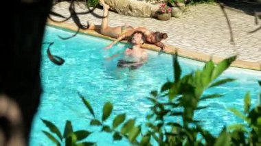 Havuzda erkek arkadaşıyla yüzen güzel bir kadın.